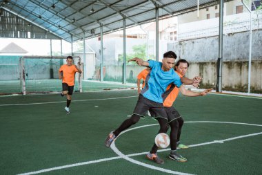 Mavi üniformalı oyuncular rakipleriyle top için kavga ediyorlar.