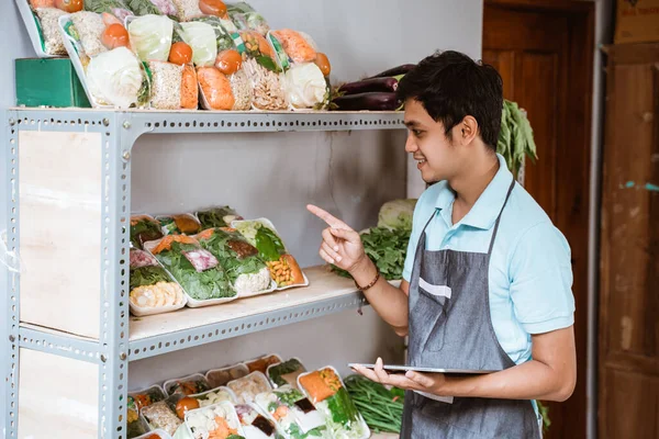 Άνθρωπος που πουλάει λαχανικά μετρώντας λαχανικά χρησιμοποιώντας ένα ψηφιακό δισκίο — Φωτογραφία Αρχείου