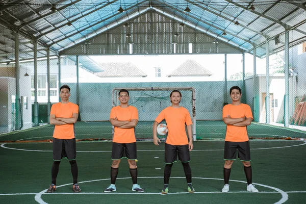 Czterech futsal graczy stojących w rzędzie niosąc piłkę — Zdjęcie stockowe