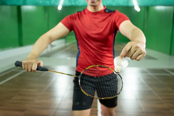 Framifrån av badminton spelare hand håller skyttel och racket — Stockfoto