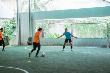 Futsal oynarken kaleciye top süren bir oyuncu