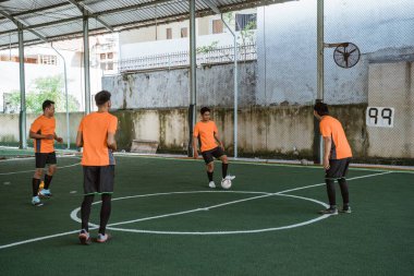 Dört futsal oyuncu pas pratiği yapıyor.