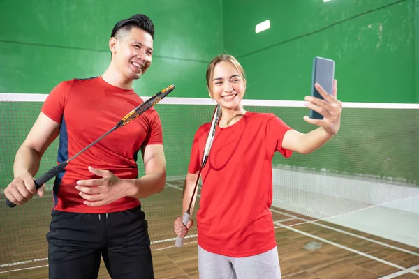 Kvinnliga och manliga badminton spelare selfie tillsammans med mobiltelefoner — Stockfoto