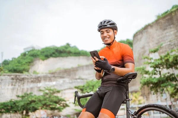 Ciclista de bicicleta de carretera sentado en su bicicleta mientras usa el teléfono móvil — Foto de Stock