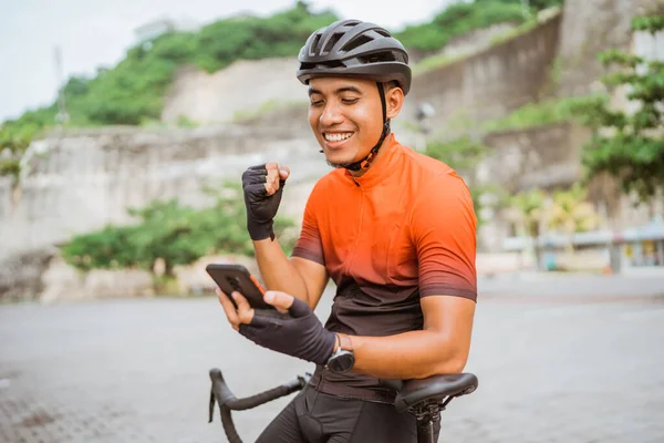 Ciclista de bicicleta de carretera sentado en su bicicleta mientras usa el teléfono móvil — Foto de Stock