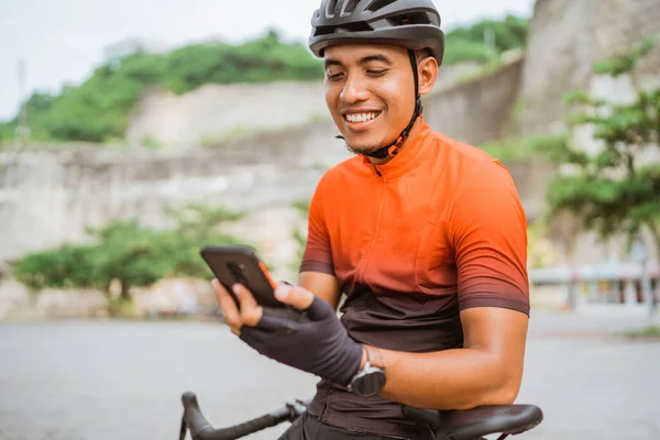 携帯電話を使いながら自転車に座っているロードバイクのサイクリストは — ストック写真