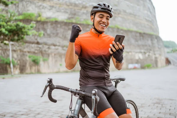 Ciclista de bicicleta de carretera sentado en su bicicleta mientras usa el teléfono móvil — Foto de Stock