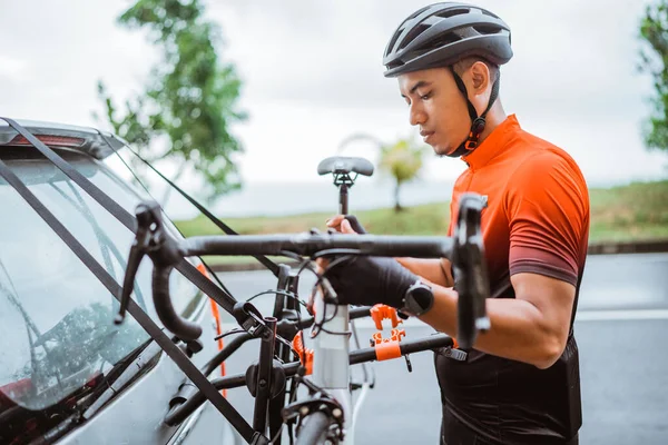 Hombre ciclista descargando su bicicleta en un bastidor de su coche — Foto de Stock