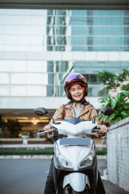 Motosiklet sürerken kask takan çekici bir kadın.