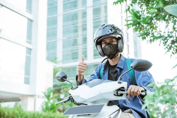 Man wearing helmet with thumbs up on a motorcycle — Stock Photo, Image
