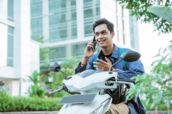 오토바이를 타면서 핸드폰을 사용하는 아시아 남자 — 스톡 사진