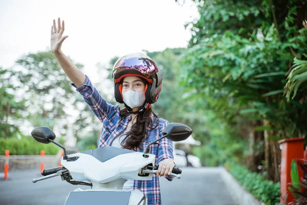 Asiatin mit Helm und Maske winkt beim Motorradfahren — Stockfoto