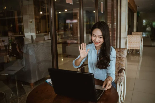 Bilgisayarla çalışırken selam veren Asyalı bir kadın. — Stok fotoğraf