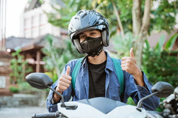 Man wearing helmet and mask with thumbs up on motorcycle — Stock Photo, Image