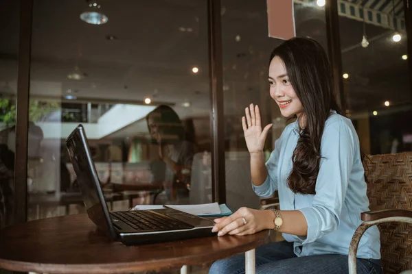 Woman with greeting gesture at monitor screen using laptop — Stock Photo, Image