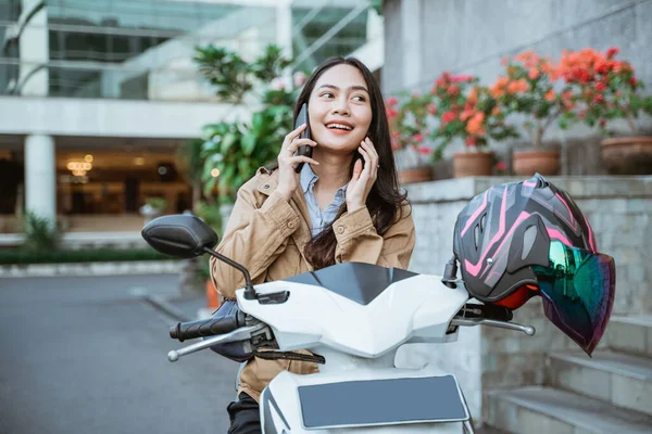 Schöne Frau macht einen Anruf auf einem Motorrad — Stockfoto
