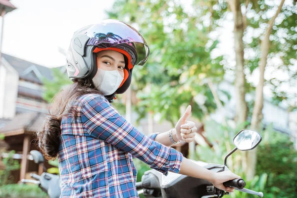 Frau trägt Helm und Maske mit erhobenen Daumen während der Fahrt — Stockfoto