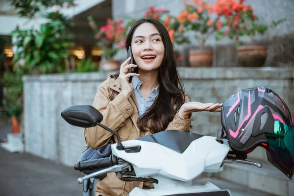 Kobieta dzwoni za pomocą telefonu komórkowego podczas jazdy na motocyklu — Zdjęcie stockowe