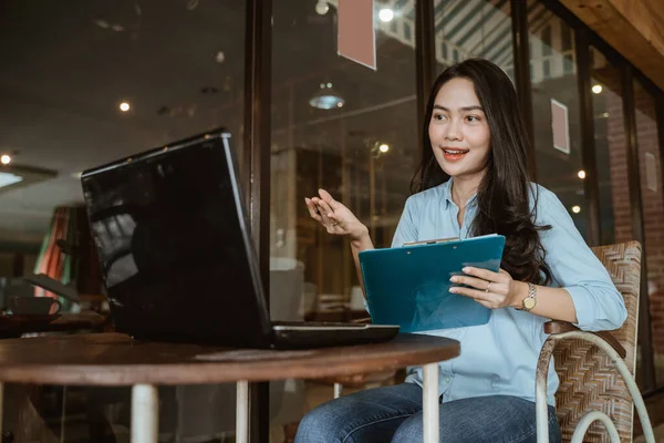 Freelance asian woman working using laptop and clipboard during meeting — Stock Photo, Image