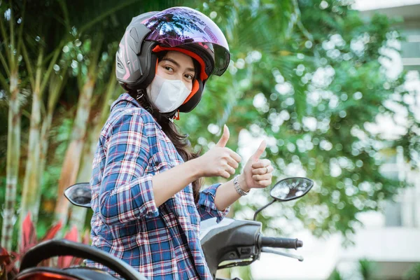 Mulher usando capacete e máscara com polegares para cima na moto — Fotografia de Stock