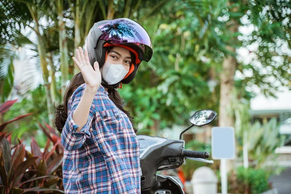 Asiatico donna indossando casco e maschera agitando mentre arresto equitazione — Foto Stock