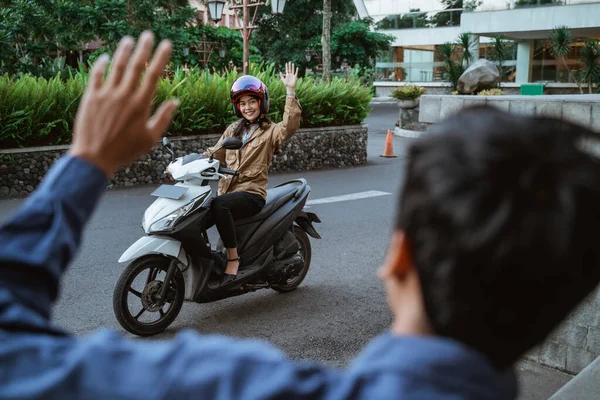 오토바이를 타고 누군가와 손을 흔들고 있는 이시아 여자 — 스톡 사진
