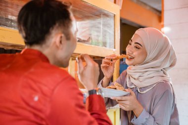 Müslüman çift geleneksel yemek standında oturmuş, iftar zamanını bekliyorlar.