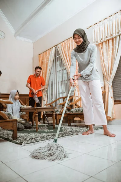 Asiática velada madre fregando el suelo mientras limpia la casa — Foto de Stock