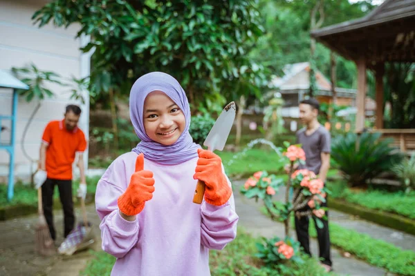 Gadis tersenyum memakai sarung tangan dengan jempol memegang sekop tanah — Stok Foto