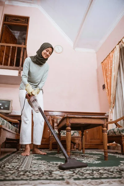 Woman wearing hijab using vacuum when cleaning carpet — Stock Photo, Image