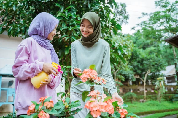 Madre e hija charlando mientras pulverizan plantas de flores en el jardín —  Fotos de Stock