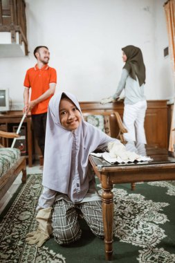 Kızım oturma odasındaki masayı silerken gülümsüyor.