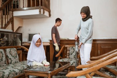 Peçeli anne vakum kullanarak evi birlikte temizliyor.