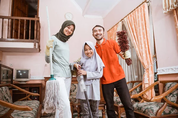 Kebahagiaan keluarga Muslim memegang alat pembersih sambil membersihkan ruangan — Stok Foto