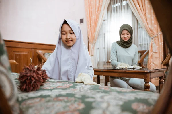 Putri membersihkan kursi dengan debu dengan ibu di ruang tamu — Stok Foto