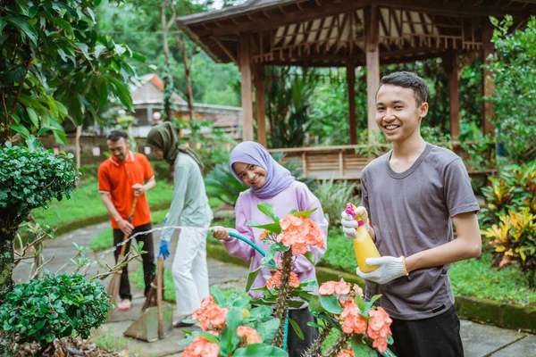 정원에서 가족 과 함께 정원을 가꾸면서 화초에 물을 주는 두 자녀 — 스톡 사진