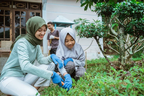 Мусульманская азиатская мать и дочь вместе занимаются садоводством во дворе — стоковое фото