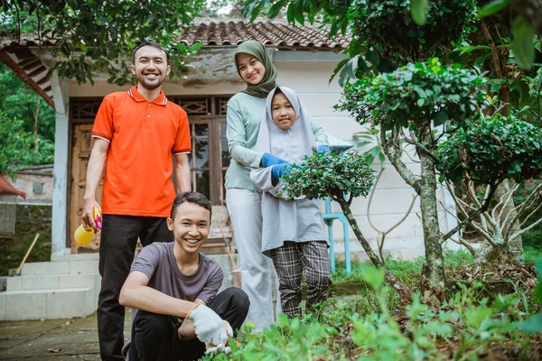 Ayah, ibu dan dua anak tersenyum sambil berkebun bersama — Stok Foto