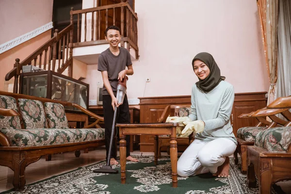 Ibu mengenakan jilbab dan anak tersenyum sambil membersihkan karpet — Stok Foto