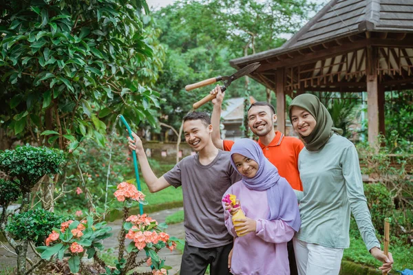 Padre, madre y dos hijos sonriendo mientras hacen jardinería con la familia —  Fotos de Stock