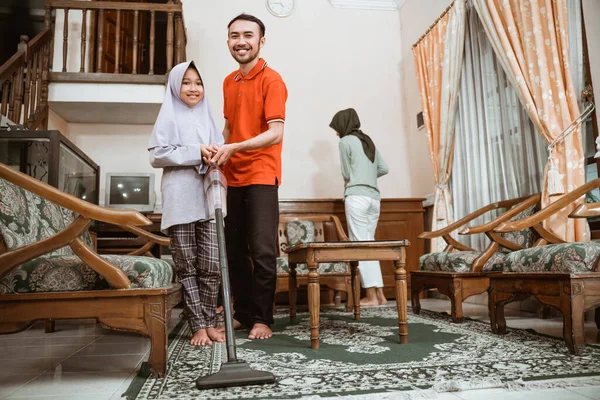 Padre e hija sonriendo mientras usan el vacío para limpiar la alfombra — Foto de Stock