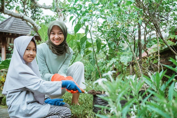 Mãe e filha sorrindo ao plantar plantas em casa jardim — Fotografia de Stock