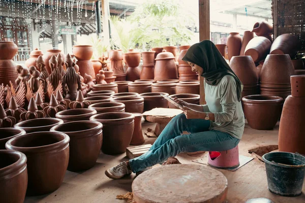 ヒジャーブのイスラム教徒の少女は陶器の間のパッドを使用して座って — ストック写真