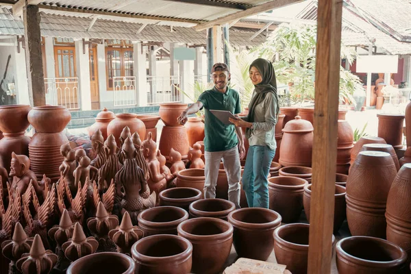 Pengrajin dengan menunjuk jari menunjukkan kerajinan tembikar untuk wanita terselubung — Stok Foto