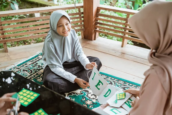 Gadis mengenakan jilbab membuat dekorasi rantai kertas bendera — Stok Foto