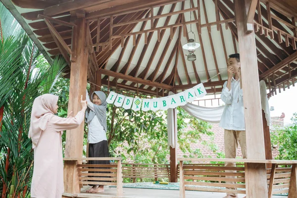 Çocuklar ve anneler çardak direklerine bayrak zincirleri takarlar.