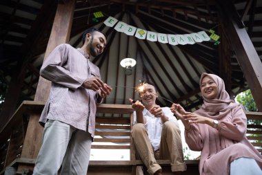 Baba, anne ve oğul Mübarek bayramını kutlarken havai fişek yakıyor.