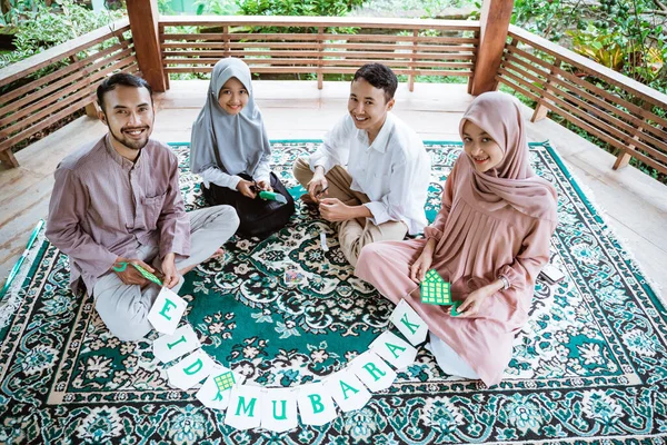 카펫 위에 앉아 종이 장식을 하고 있는 모슬렘 이시아 가족 — 스톡 사진