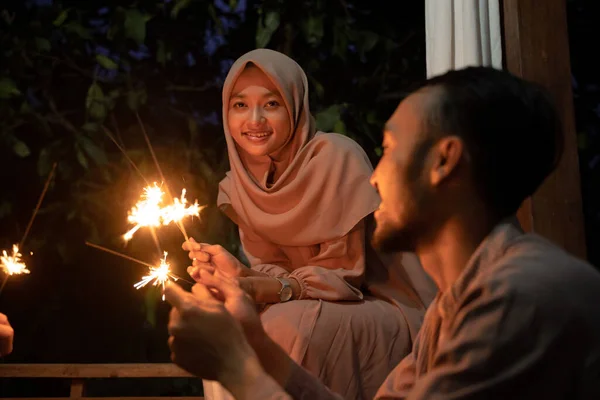 Uma mulher velada acende fogos de artifício durante a celebração — Fotografia de Stock