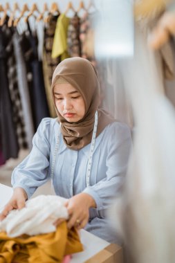 Müslüman moda tasarımcısı elbise ürünlerini kontrol ediyor.